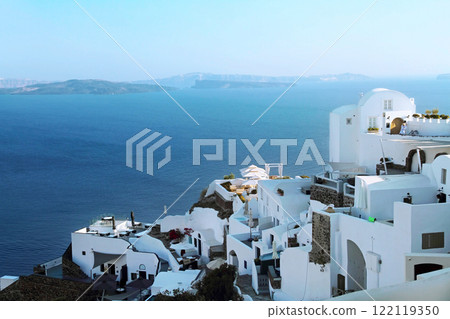 Picturesque view of the Santorini volcano caldera with traditional white houses on the mountainside in Oia against the backdrop of the blue sea. 122119350