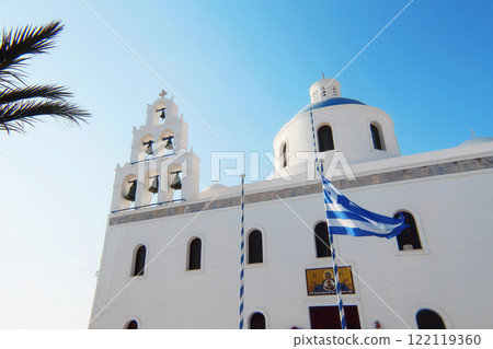 The Orthodox Church of Panagia Akathistos Hymn Holy with the Greek flag in front of the facade. Oia, Santorini. 122119360