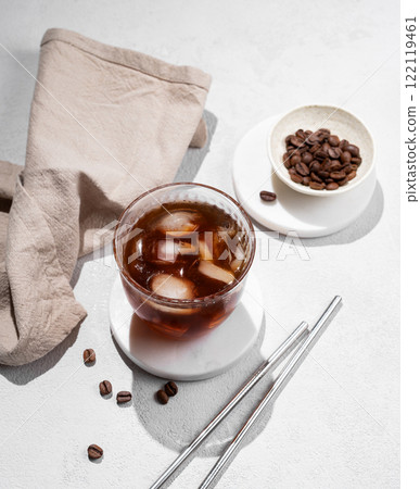 Cold brew coffee in a glass with ice on a light texture background with coffee beans 122119461