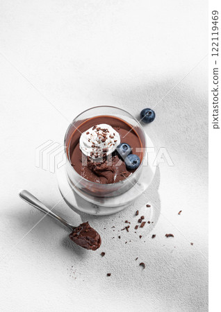 Chocolate pudding in a glass with whipped cream and fresh blueberry on a light background Chocolate pudding in a glass with whipped cream and fresh blueberry on a light background 122119469