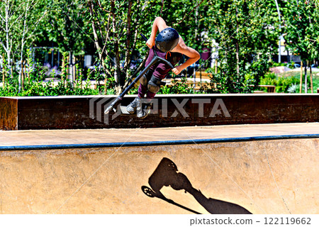 Young man practicing Scootering (Freestyle Scootering) in the new SkatePark of the central park of Igualada, Barcelona, Spain 122119662