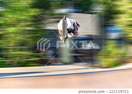 Young man practicing Scootering (Freestyle Scootering) in the new SkatePark in the central park of Igualada, Barcelona, Spain. blurred background 122119721