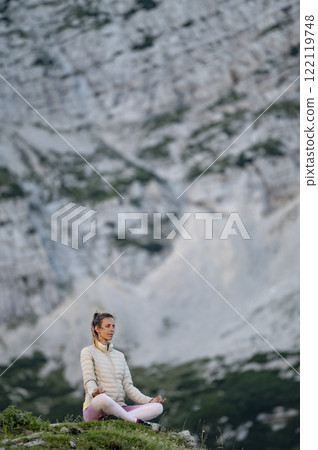 Young woman meditating on a rock in high mountains 122119748