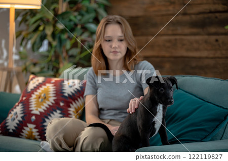 A woman taking some time to relax with her dog on a cozy couch in a lovely living room 122119827