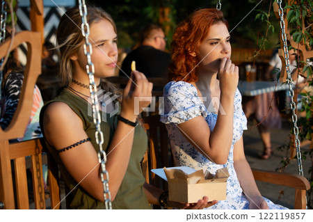 Two Friends Beautifully Enjoying Delicious Food Together on a Delightful Swing in Nature Two Friends Beautifully Enjoying Delicious Food Together on a Delightful Swing in Nature 122119857