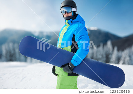 Portrait of man at ski resort on the background mountains holds snowboard. Wearing ski glasses Portrait of man at ski resort on the background mountains holds snowboard. Wearing ski glasses 122120416