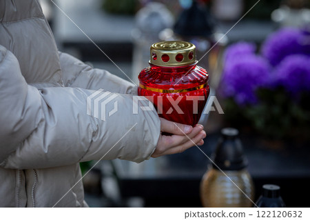 A Person Holding a Lantern at a Cemetery During a Heartfelt Memorial Service for Loved Ones 122120632