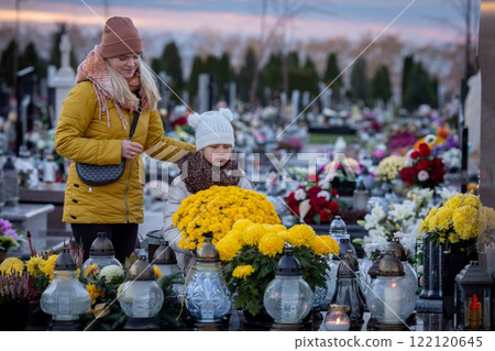 A Caring Mother and Her Child Visiting a Peaceful Cemetery with Flowers and Lanterns in hand A Caring Mother and Her Child Visiting a Peaceful Cemetery with Flowers and Lanterns in hand 122120645