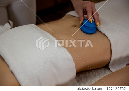 Enjoy a relaxing massage therapy with a soothing blue tool gently applied to your abdomen 122120732