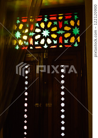Window with Arabic colored lattice, soft curtain dropped on side and dim light 122120900