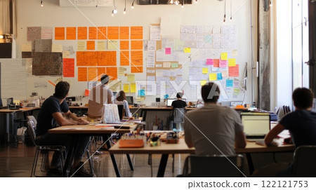 Coworkers collaborate in a modern office, brainstorming ideas on a large wall covered in sticky notes. Coworkers collaborate in a modern office, brainstorming ideas on a large wall covered in sticky notes. 122121753