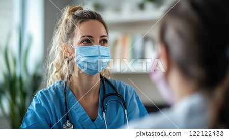 A woman in a blue scrubs is wearing a mask 122122488