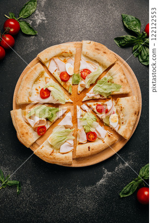 Freshly sliced gourmet salad pizza with lettuce, turkey, and cherry tomatoes on a wooden plate Freshly sliced gourmet salad pizza with lettuce, turkey, and cherry tomatoes on a wooden plate 122122553