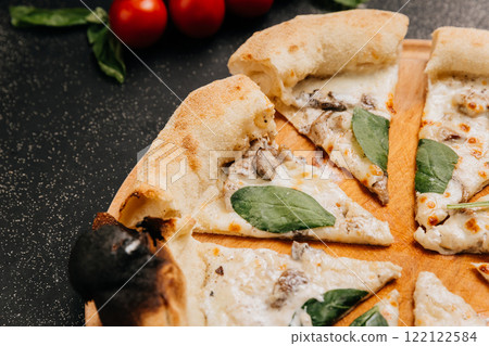 Wood-fired white pizza slices with mushrooms, spinach, and creamy cheese on a rustic wooden plate Wood-fired white pizza slices with mushrooms, spinach, and creamy cheese on a rustic wooden plate 122122584