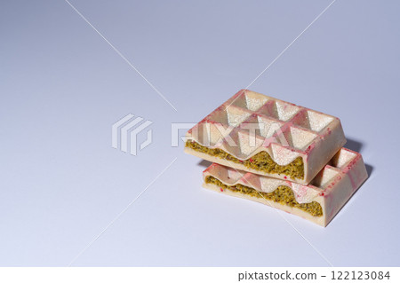 Trend white Dubai chocolate with pistachio, dried raspberry, tahini and kadaif, on white background with copy space, isolated, showing the filling. Confectionery and handmade sweets, chocolatier Trend white Dubai chocolate with pistachio, dried raspberry, tahini and kadaif, on white background with copy space, isolated, showing the filling. Confectionery and handmade sweets, chocolatier 122123084