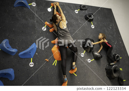 Courageous girl climbing artificial rock wall with 122123334