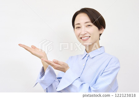 Woman pointing to the left with her palm on a white background 122123818
