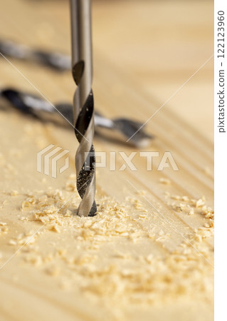 metal drill bit and pine wood board during operation metal drill bit and pine wood board during operation 122123960