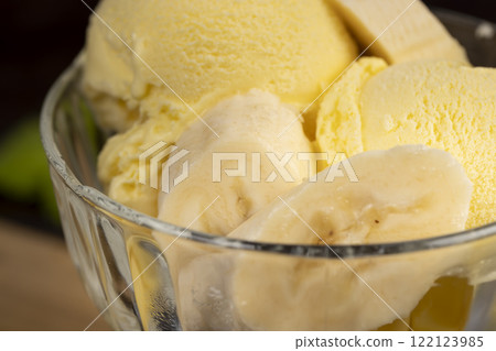 creamy ice cream with yellow banana slices in a glass cup 122123985