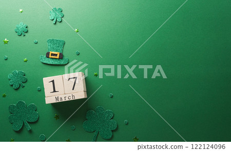 Happy St Patrick's Day decoration concept made from shamrocks ( clover leaf), wooden calendar and leprechaun hat on green background. Happy St Patrick's Day decoration concept made from shamrocks ( clover leaf), wooden calendar and leprechaun hat on green background. 122124096