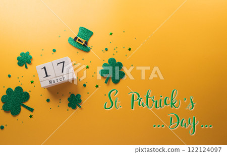Happy St Patrick's Day decoration concept made from shamrocks ( clover leaf), wooden calendar and leprechaun hat on yellow background. 122124097