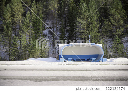 A Snowy Bus Stop, Perfectly Nestled Amongst Tall Pine Trees, in a Loving Calm and Peaceful Landscape 122124374