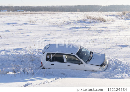 A car is stuck in a snowy landscape, surrounded by cold conditions and blizzard challenges Ice, A car flew off the road into the snow into a ditch on the side of the road, Accidents and road safety in 122124384