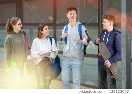 Carefree teen students walking outside school 122125667