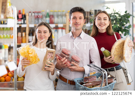 In store, family with purchases in hands looking for something on shelf of showcase In store, family with purchases in hands looking for something on shelf of showcase 122125674