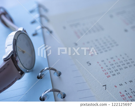 A calendar, a notebook and a watch on the table A calendar, a notebook and a watch on the table 122125697