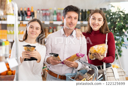 Dad, mom and daughter look at and choose pasta in selling area of shop Dad, mom and daughter look at and choose pasta in selling area of shop 122125699