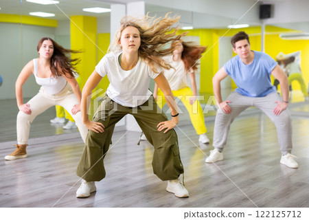 Happy heenagers in dance hall studying new movements, smiling and having fun 122125712