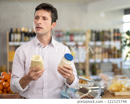 Man in light shirt choose and buy mayonnaise in store Man in light shirt choose and buy mayonnaise in store 122125746
