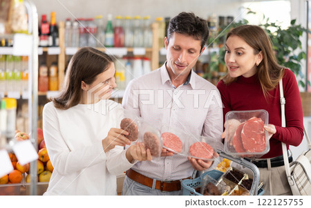 Family with teenage girl choosing hamburger or beef entrecote in grocery Family with teenage girl choosing hamburger or beef entrecote in grocery 122125755