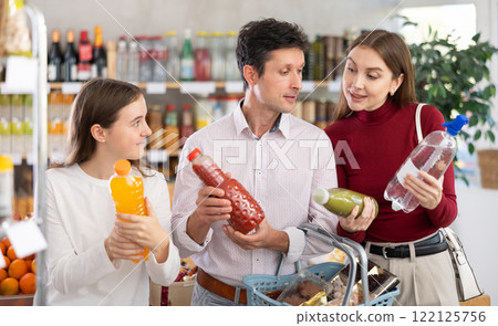Family with teenage girl choosing non-alcoholic drinks in grocery 122125756