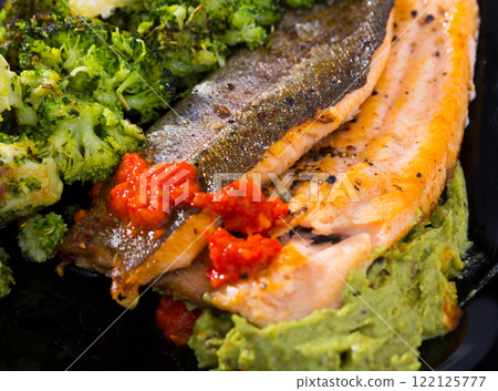 Grilled trout with broccoli, guacamole and tomato sauce 122125777