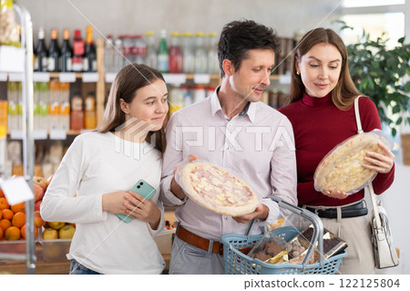 Father, mother and daughter choose various of pizza in shop 122125804