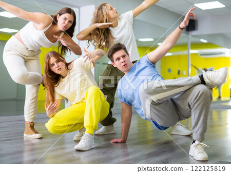 Teenage girls and a boy performing breakdance poses in dance hall 122125819