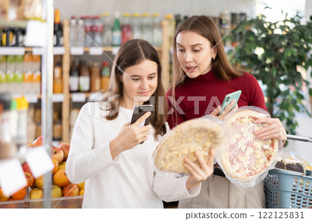 Mom and daughter scan pizza on phone Mom and daughter scan pizza on phone 122125831