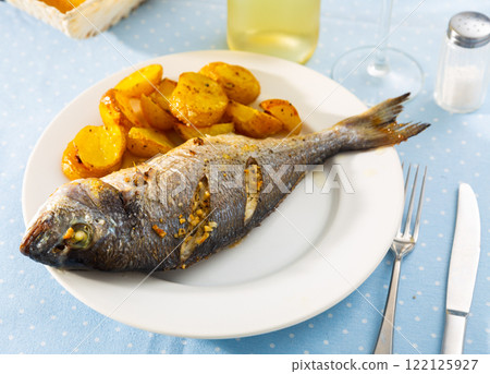 Baked dorado with potatoes on plate 122125927