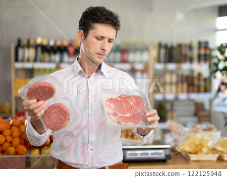Adult man choosing hamburger or entrecote in grocery store 122125948