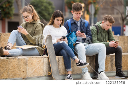 Teenage friends holding phones 122125956