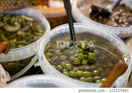 Heap of green olives with pits in buckets 122125981