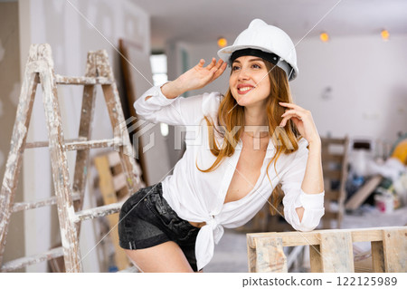 Seductive young woman poses in a hardhat and in a revealing outfit Seductive young woman poses in a hardhat and in a revealing outfit 122125989