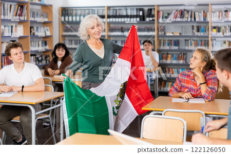 Interesting story about Mexico while teaching high school students in school library. Teacher holds flag of Mexico in her hands 122126050