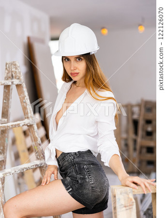 Seductive young woman poses in a hardhat and in a revealing outfit Seductive young woman poses in a hardhat and in a revealing outfit 122126070