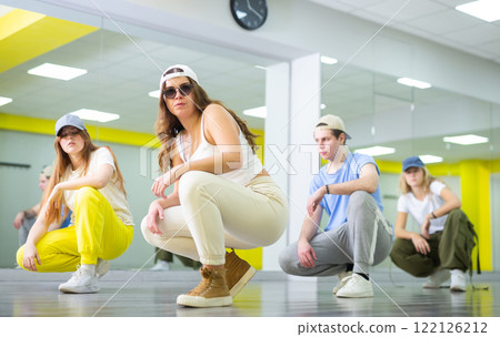 Active positive teenagers in casual wear performing dance elements during lesson in modern fitness studio 122126212