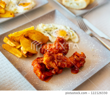 Spicy chicken with baked potato and fried egg 122126330