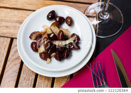 In round plate there are large shiny ripe black olives with stone 122126364