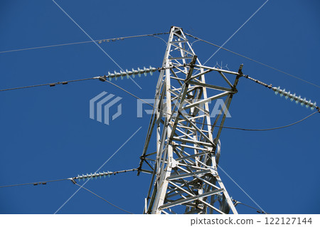 Electricity pylon transporting energy through cables under blue sky Electricity pylon transporting energy through cables under blue sky 122127144